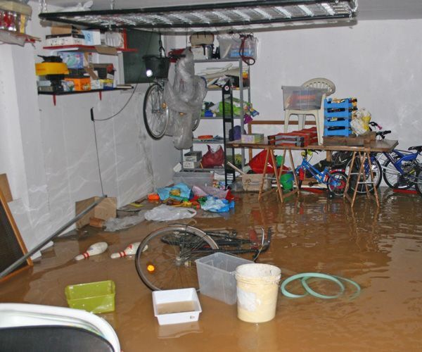 Oversvømmet kælder med vand på gulvet, cykler og opbevaringskasser – typisk scenarie efter skybrud eller kraftigt regnvejr