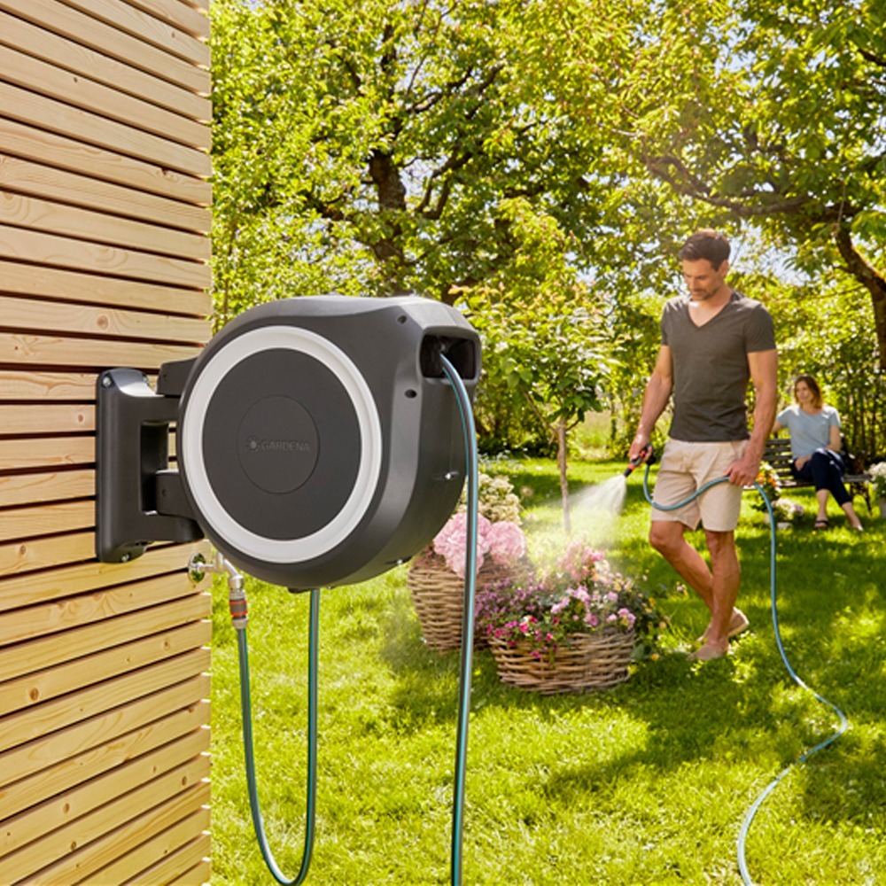 Bruger interagerer med Gardena RollUp M/L 25m, trækker slangen ud i en haveindstilling.