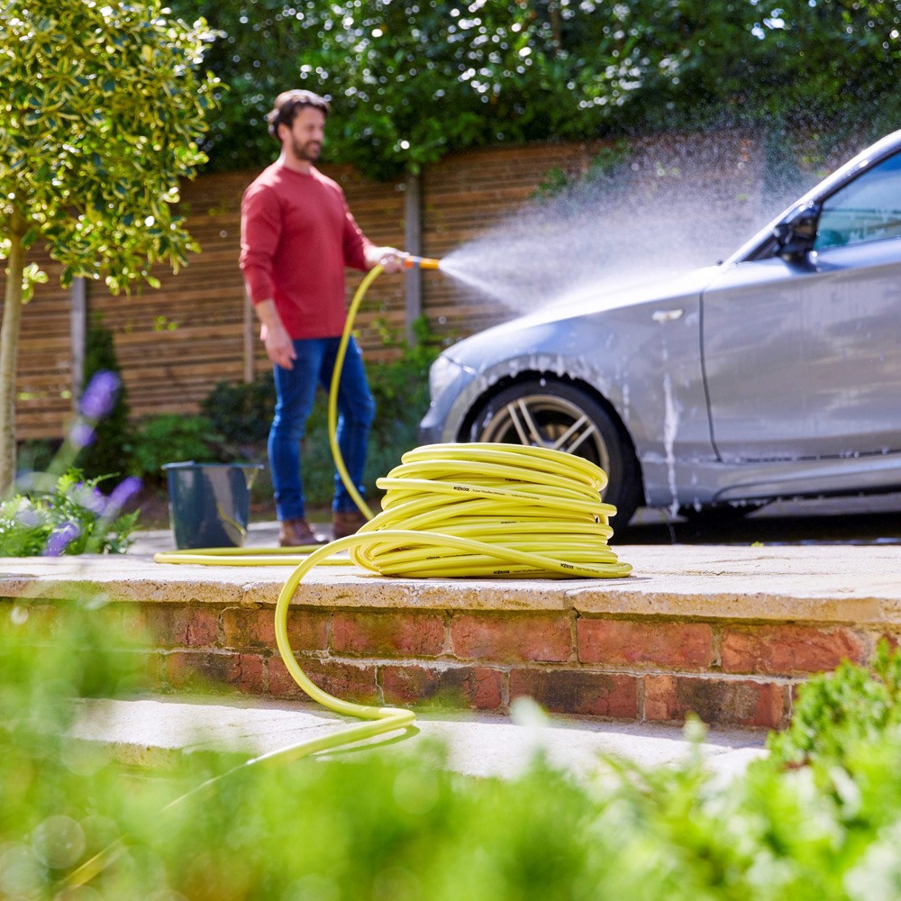 Mand vasker bilen med Hozelock Ultimate haveslange 50 m