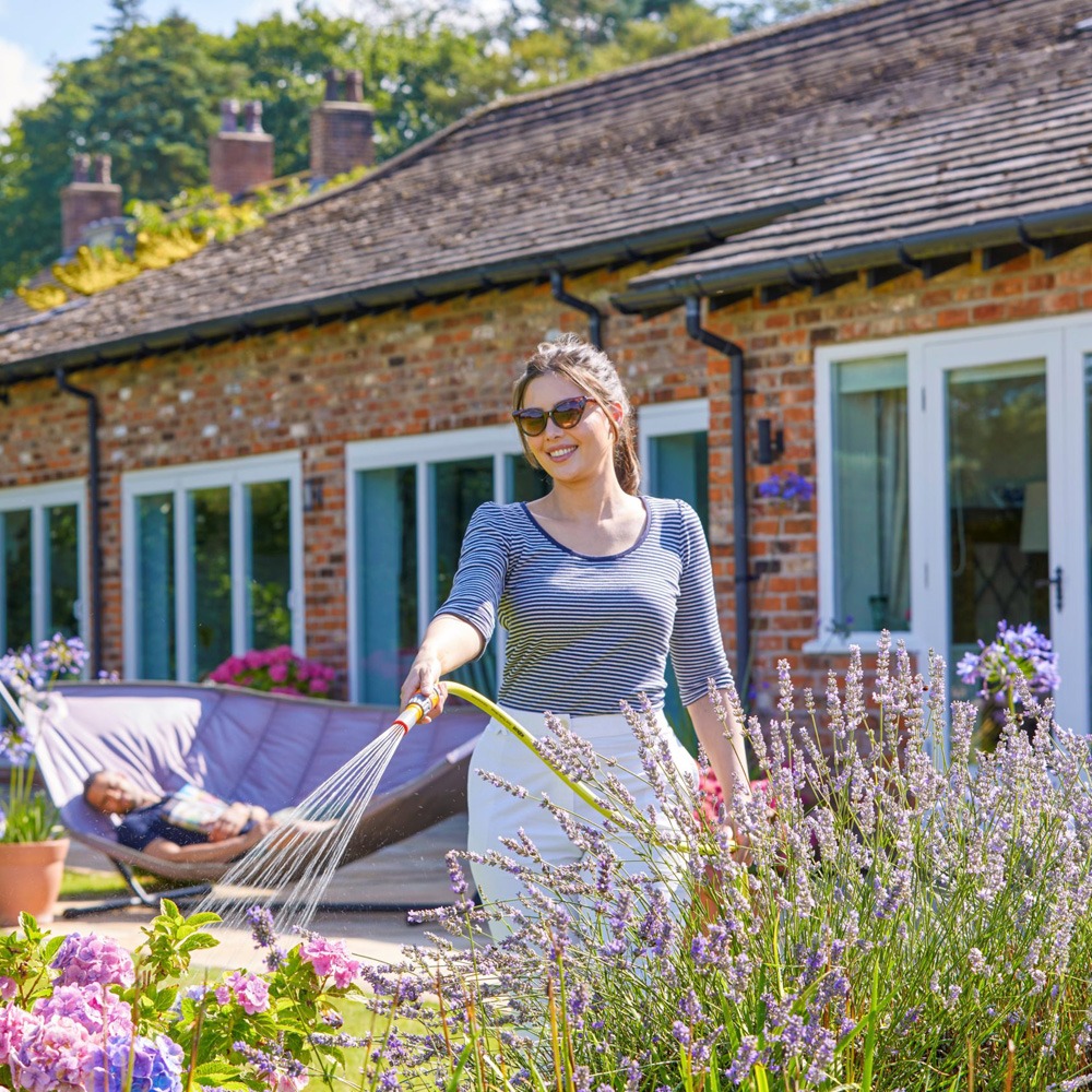 Kvinde vander blomster med Hozelock Ultimate 50 m haveslange